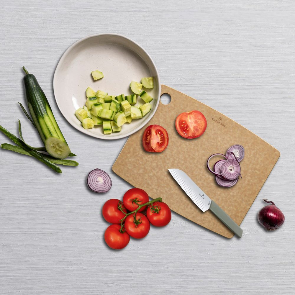 Gekochte Tomaten, Zwiebelringe, Gurkenwürfel, Messer auf einem Schneidebrett.