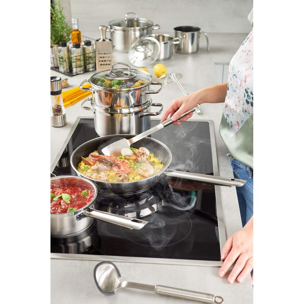 Una persona cucina la paella in una padella su un piano cottura a induzione.