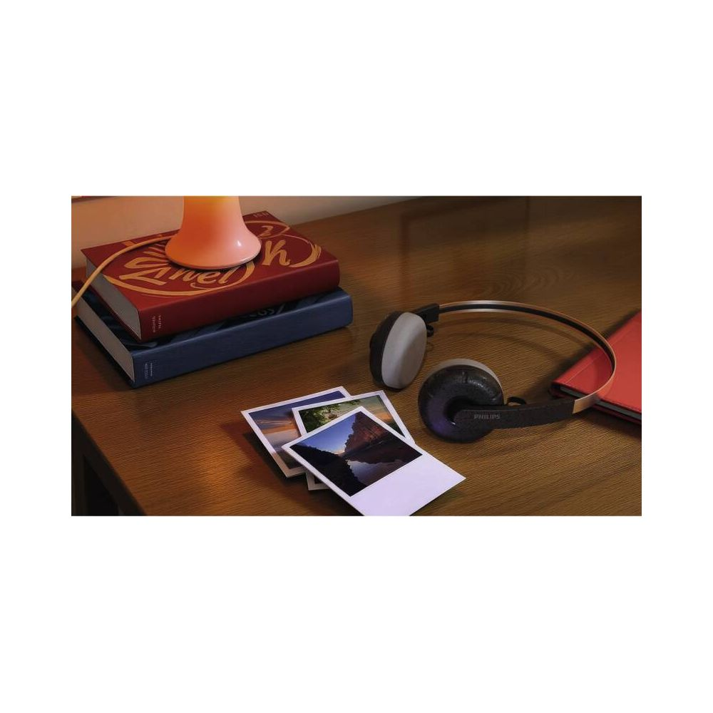 Casque posé à côté de livres et de photos sur une table en bois.