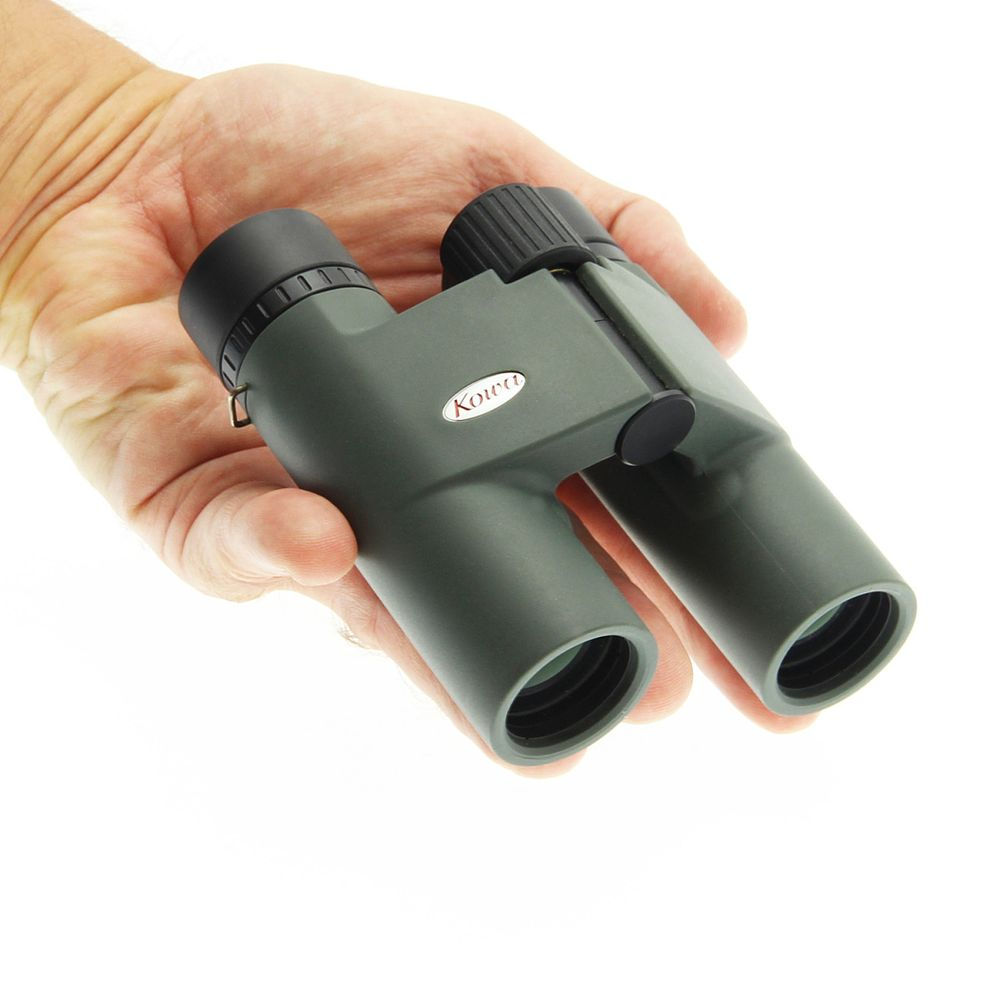 Una mano tiene un binocolo Kowa verde con accenti bianchi.