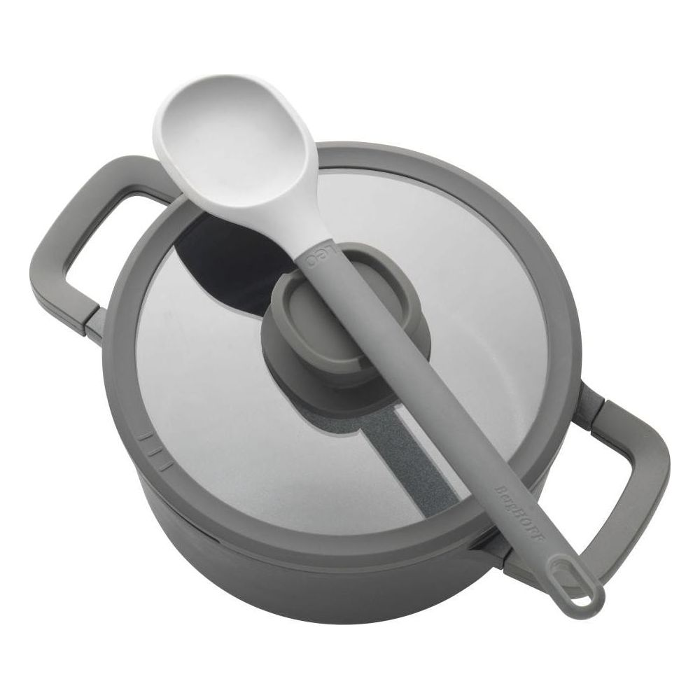 Grijze pan met glazen deksel en witte lepel. BergHOFF logo zichtbaar.