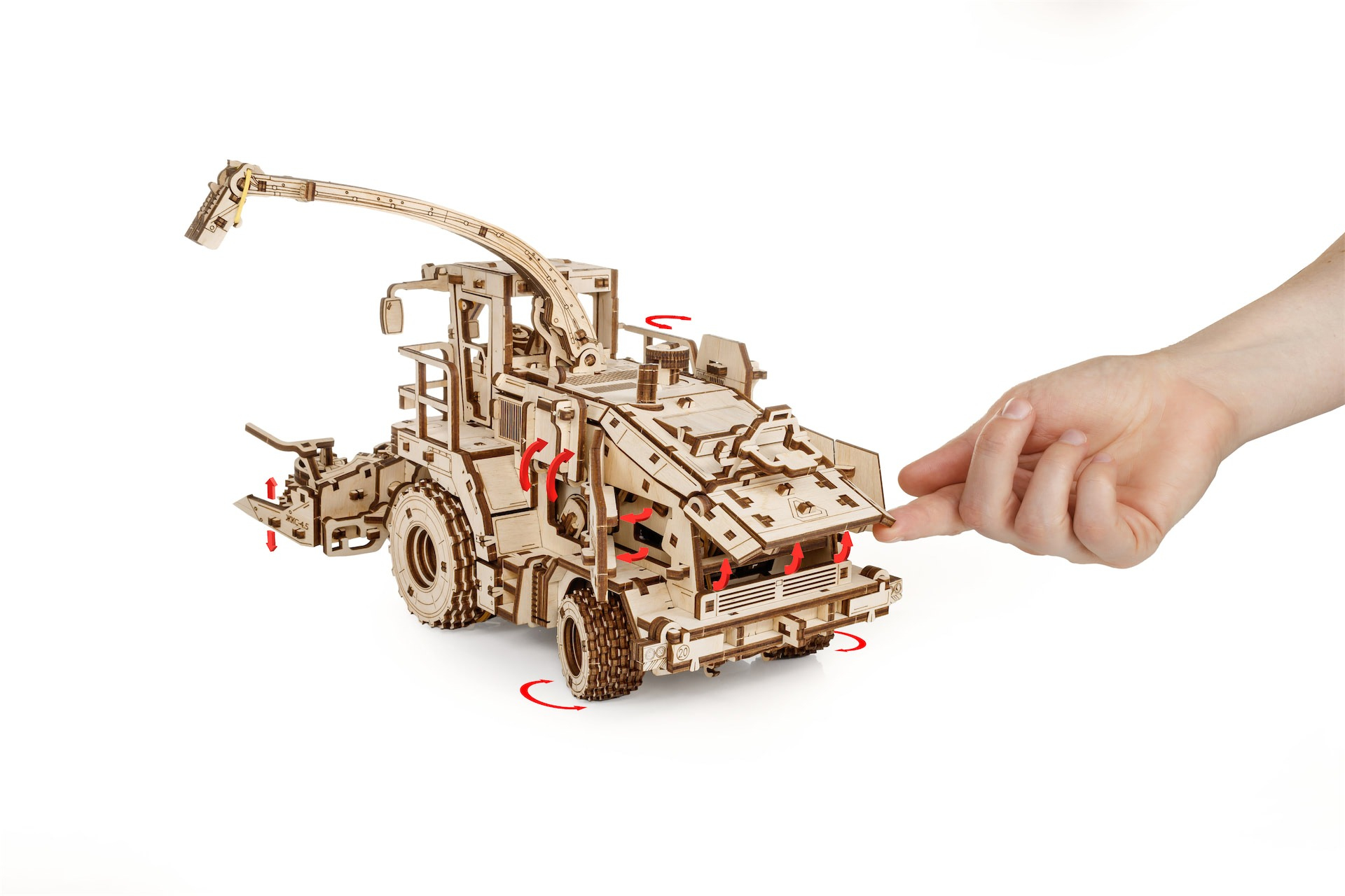 Ein Holzmodell eines Mähdreschers mit einem Kran, der von einer Hand berührt wird.