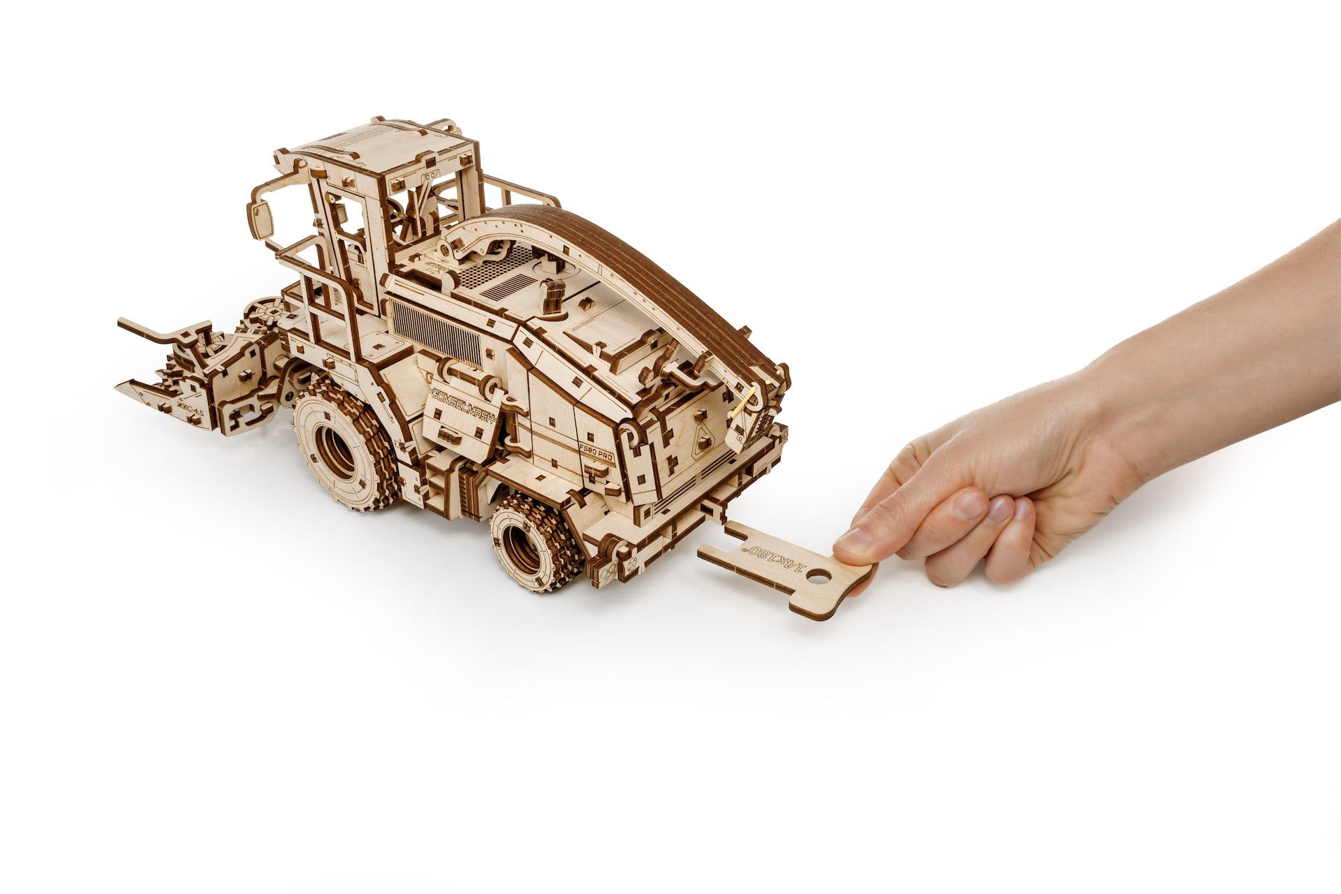 Holzmodell eines Baggers mit einem Schlüssel, der von einer Hand gehalten wird.