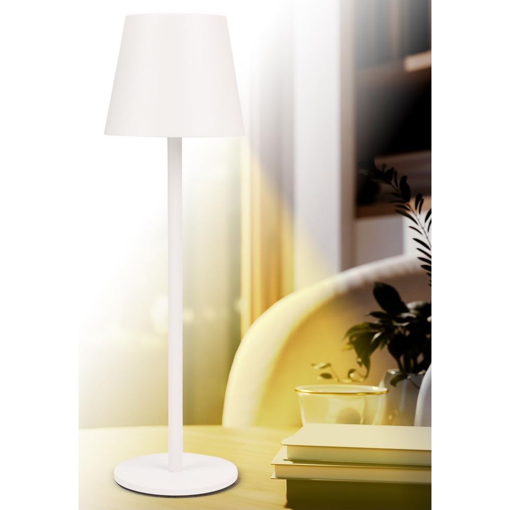Eine weiße Tischlampe steht auf einem Holztisch, daneben liegen Bücher.