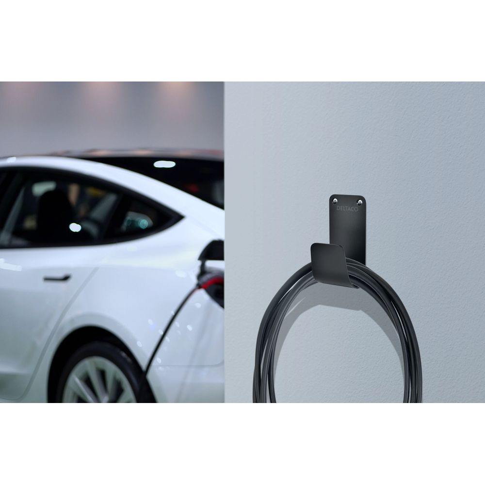 Een witte elektrische auto laadt op, ernaast een zwarte wandhaak met laadkabel.