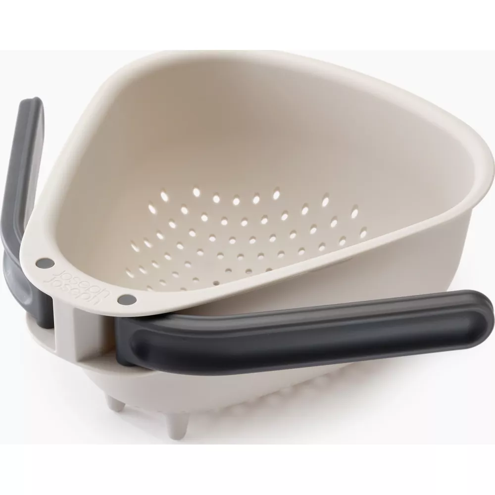 Uno scolapasta angolare beige con manici grigi su sfondo bianco.