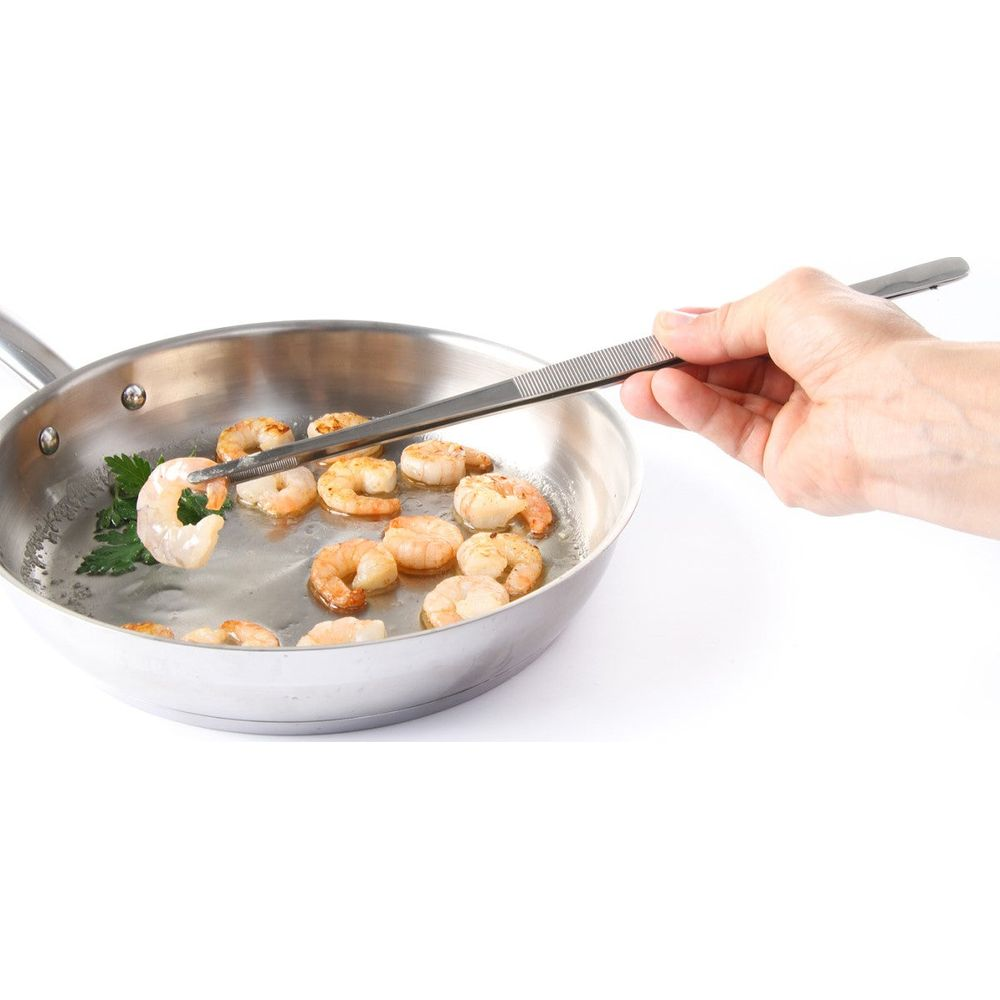 Gamberi fritti in padella con pinzette.