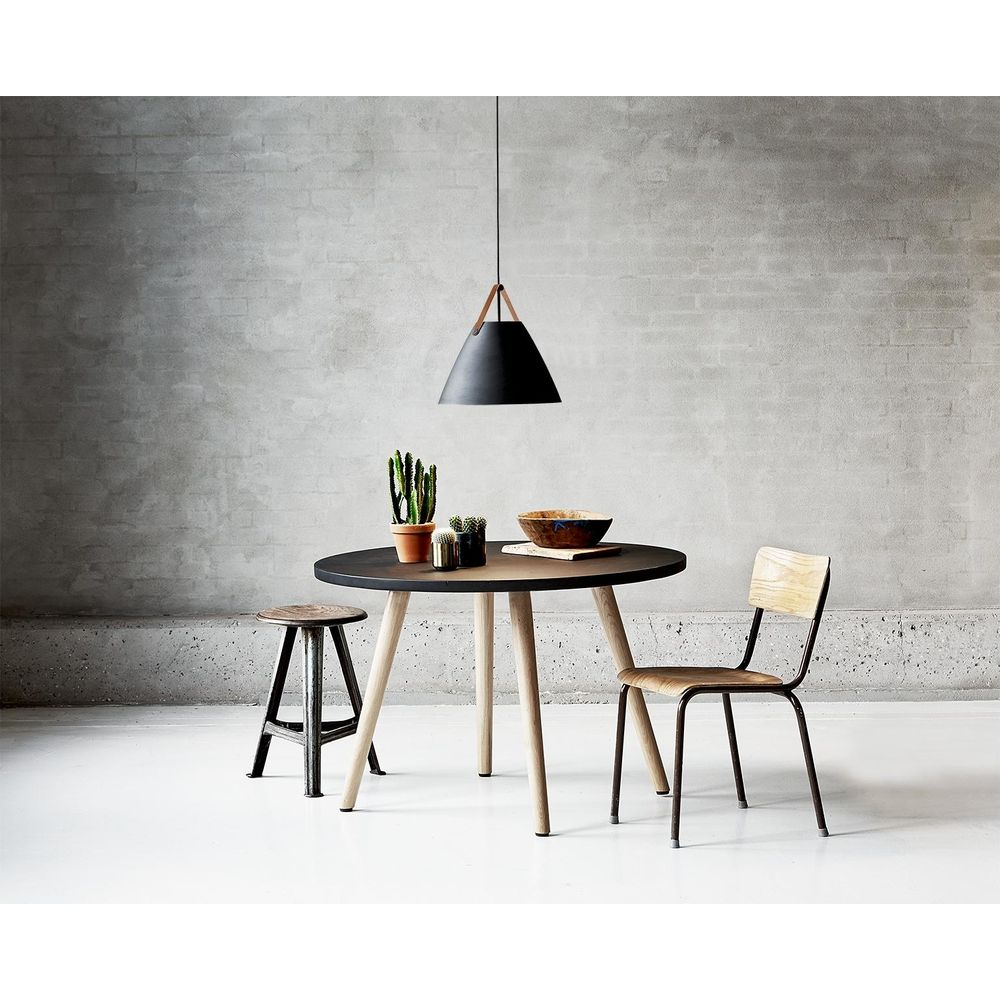 Une table ronde avec deux chaises et un tabouret devant un mur de béton.
