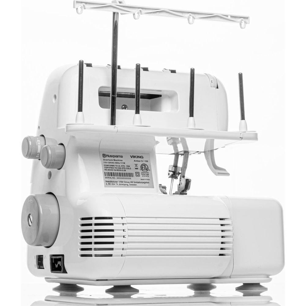 Una macchina da cucire overlock Husqvarna Viking bianca con rocchetti di filo e manopole.