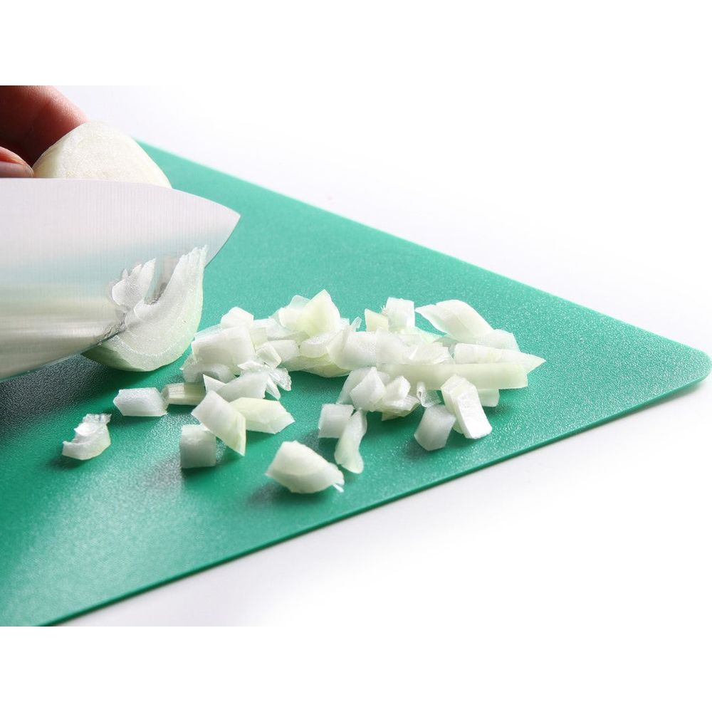 Cipolle tritate su un tagliere verde con un coltello.