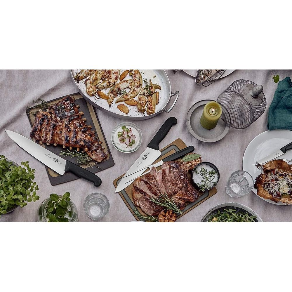 Gegrillte Rippchen und Steak mit Beilagen auf einem Tisch mit Messern und Kerze.