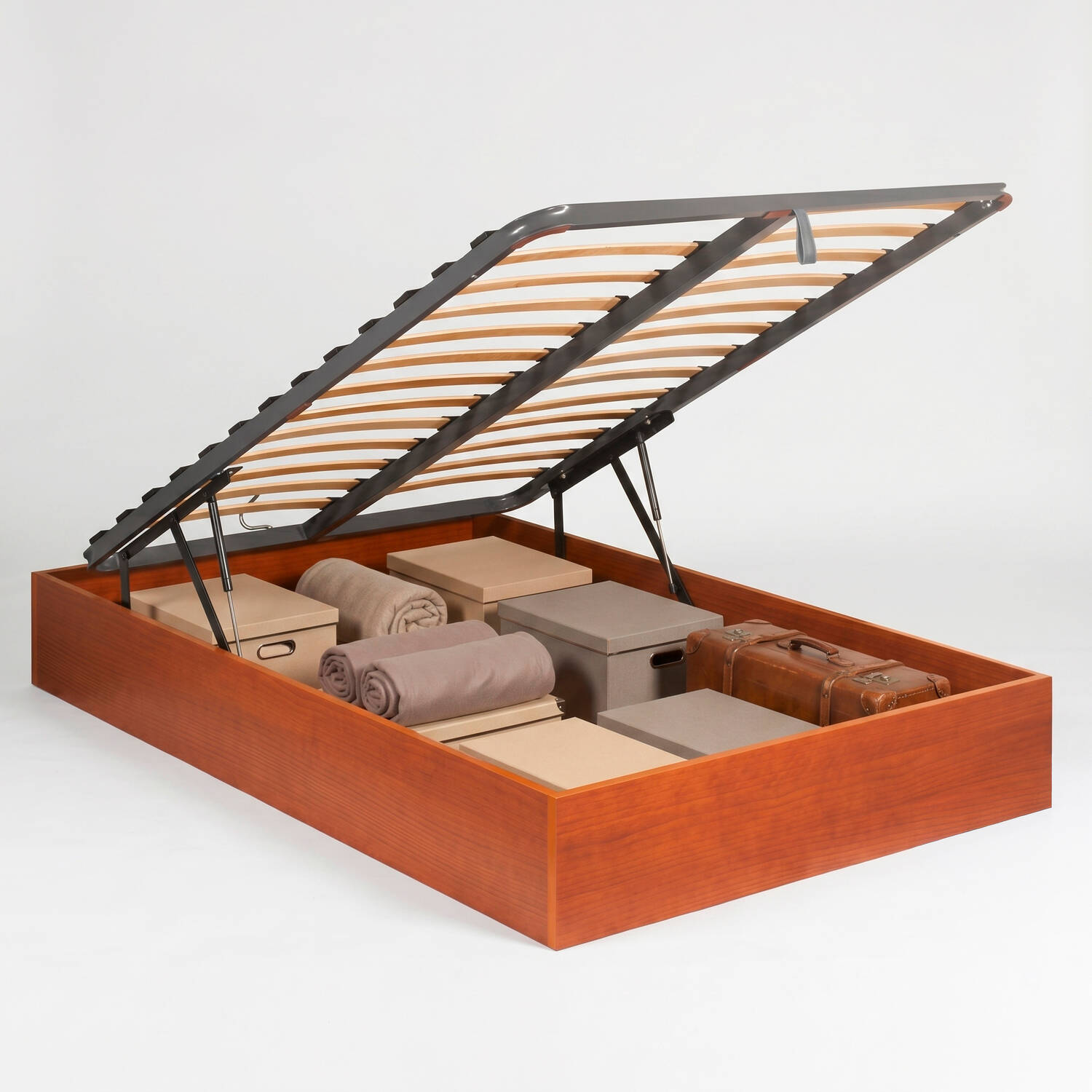 Estructura de cama de madera con almacenamiento abierto, llena de mantas, cajas y maleta.