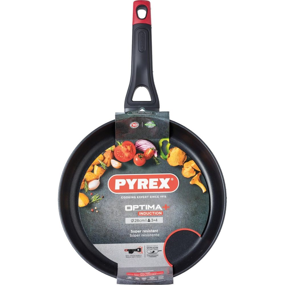Een zwarte Pyrex Optima Induction koekenpan met rood en zwart handvat. Ingrediënten omringen de pan.