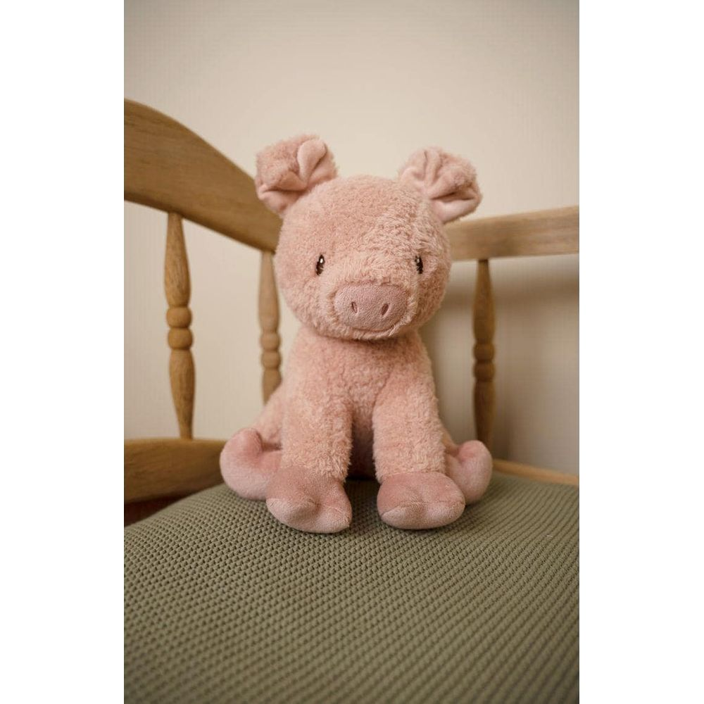 Un cochon en peluche rose est assis sur une chaise en bois avec un siège vert.