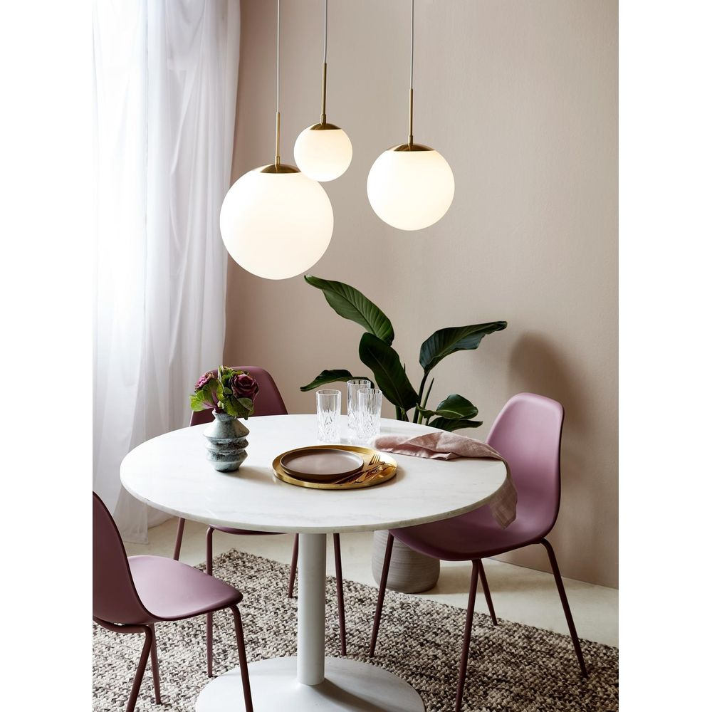 Table ronde blanche avec chaises violettes, vase à fleurs, verres et suspensions.