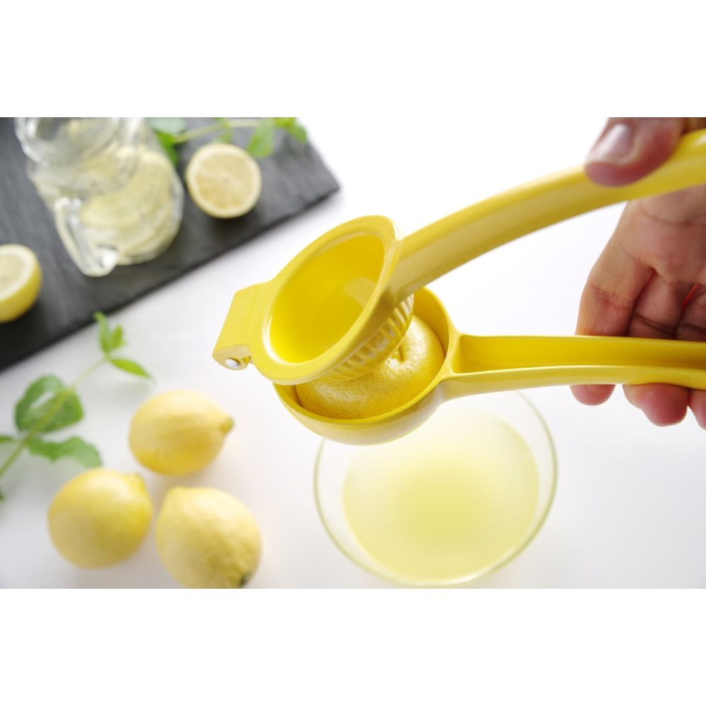 Gelber Zitronenpresse mit einer halben Zitrone, die Saft in eine Schüssel presst.