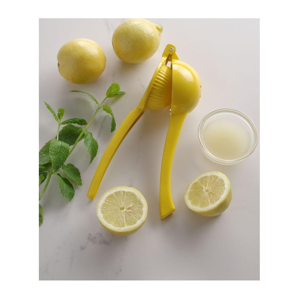Gelber Zitronenpresse mit Zitronen, Minze und Saft auf Marmorplatte.