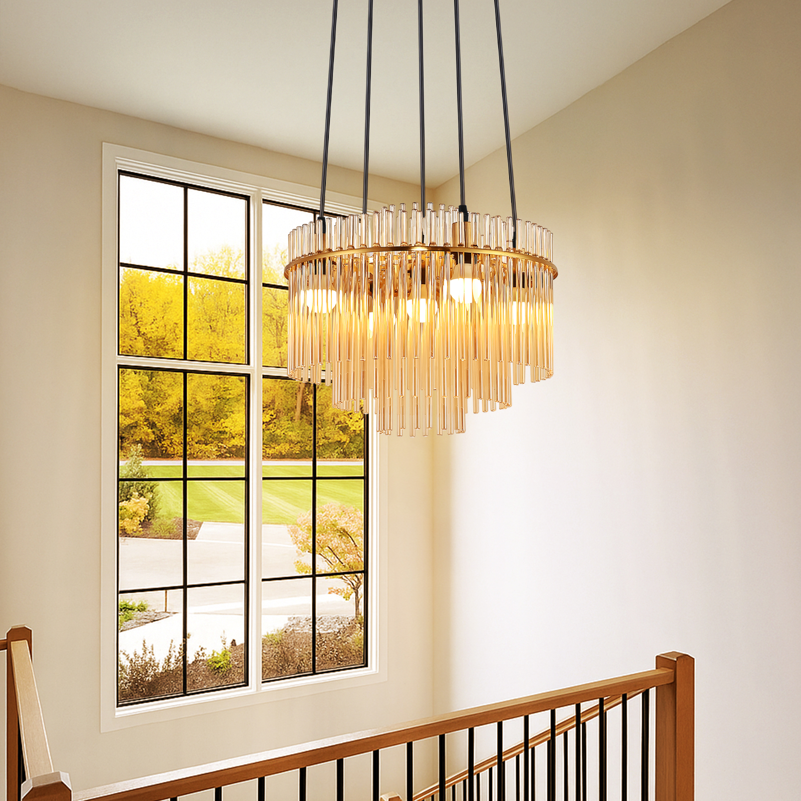 Un candelabro redondo dorado con varillas de cristal cuelga sobre una escalera con barandilla de madera.