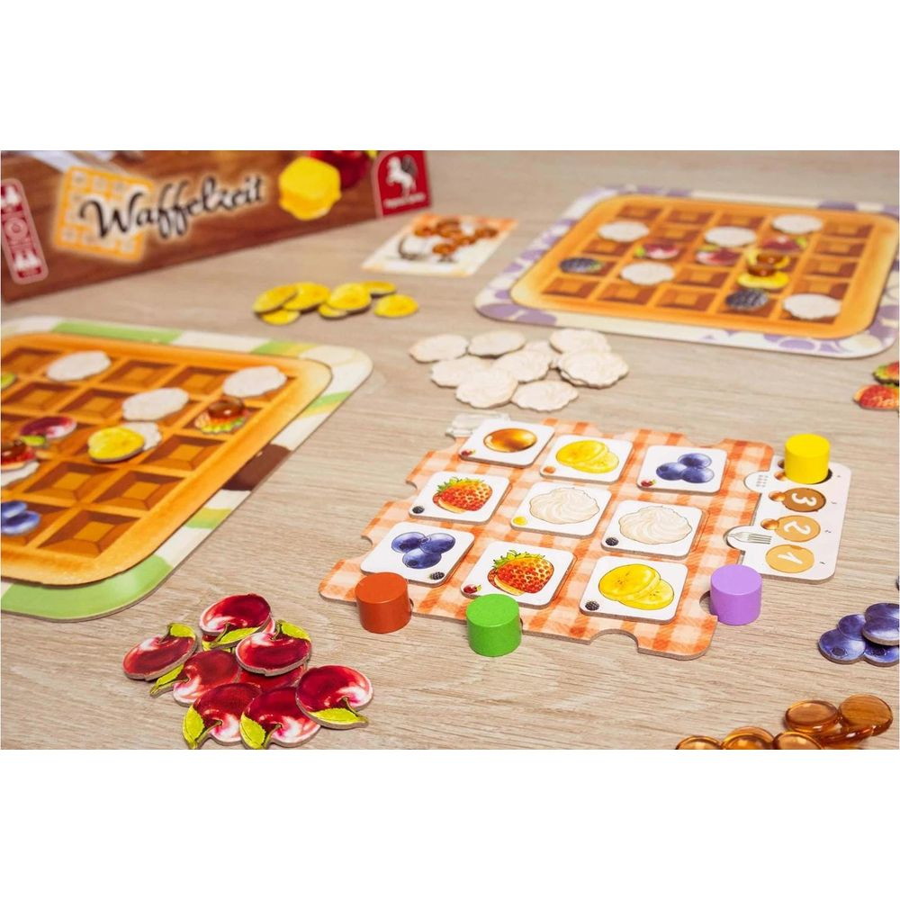Gioco da tavolo con waffle e guarnizioni di frutta. Pezzi e carte da gioco su tavolo legno.