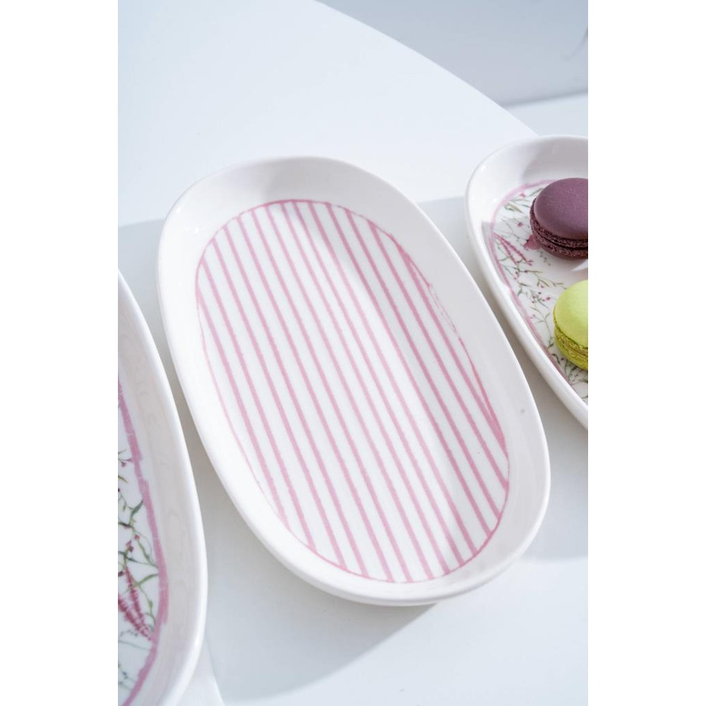 Pembe çizgili ve çiçek desenli beyaz oval tabaklar, bazıları makaronlu.