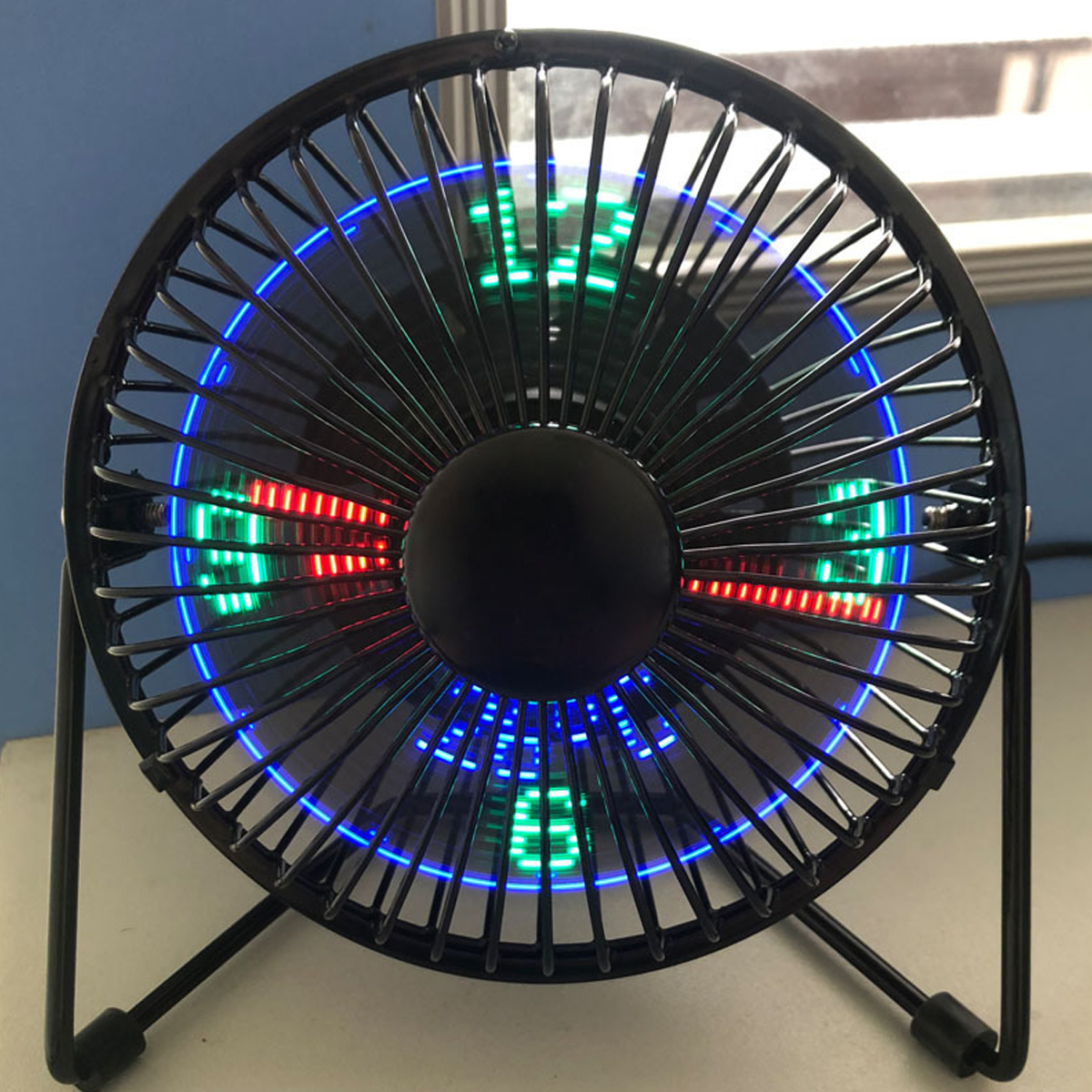Ein kleiner schwarzer Tischventilator mit blauen und grünen Lichtern.