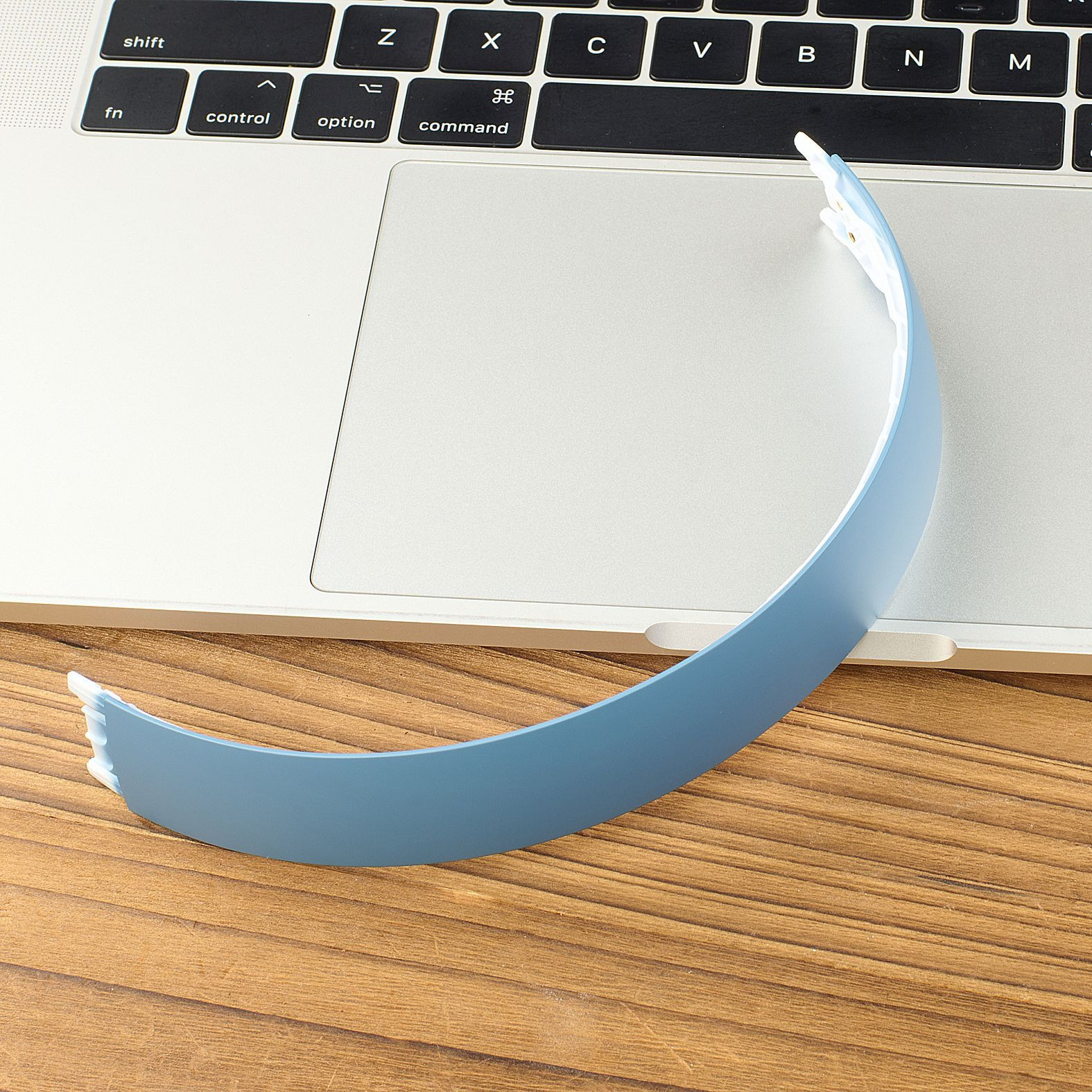 Una fascia blu poggia sulla tastiera di un laptop e su un tavolo di legno.