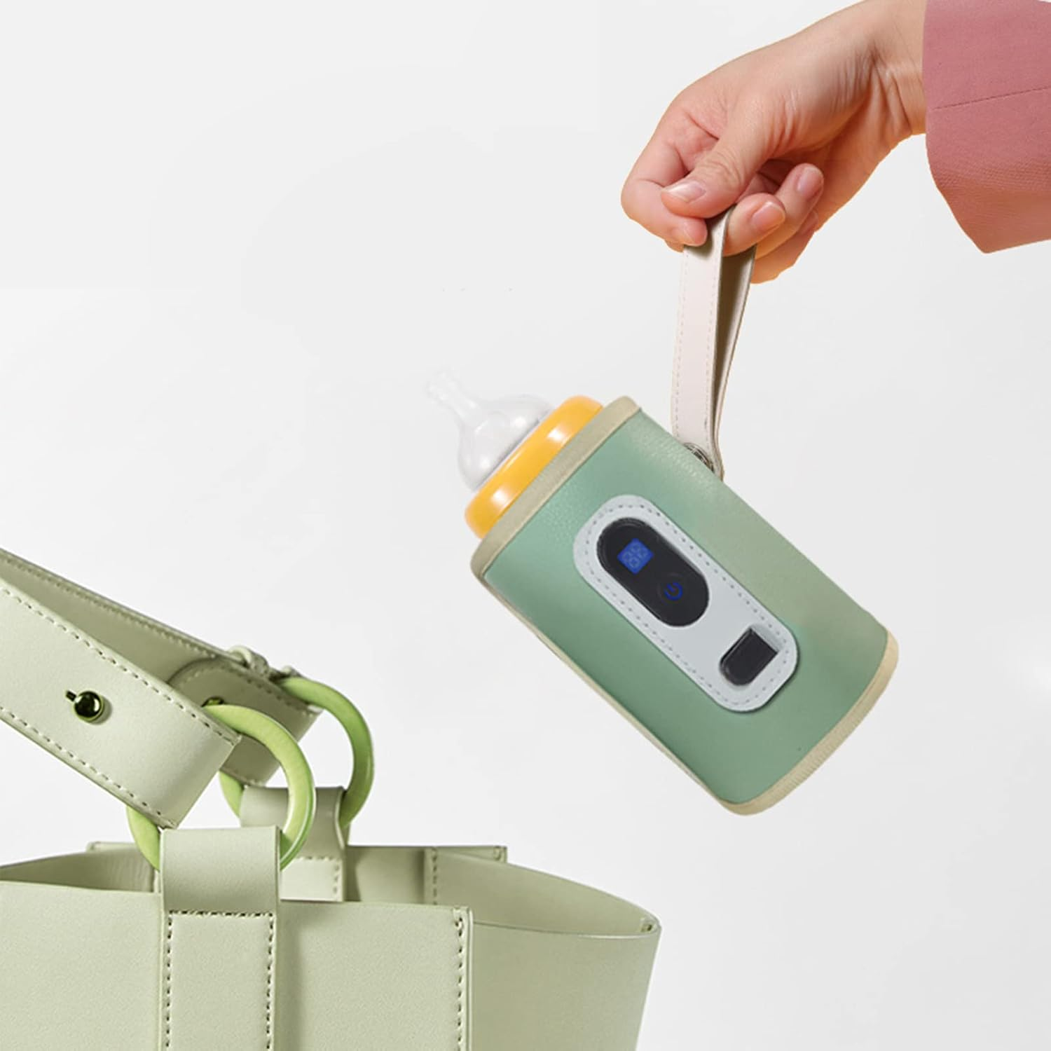 Eine Hand hält einen grünen Flaschenwärmer mit gelber Oberseite in der Nähe einer hellgrünen Tasche.