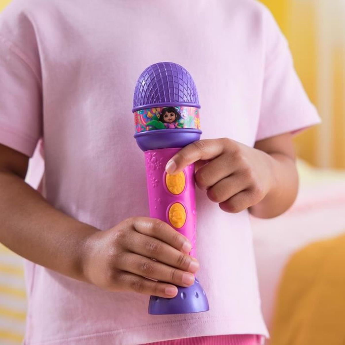 Ein Kind hält ein pinkes und lila Spielzeugmikrofon mit Dora-Motiv.