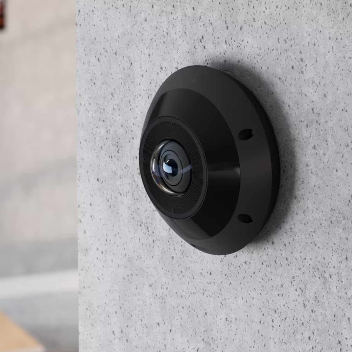 A black, spherical camera with a lens is mounted on a concrete wall.
