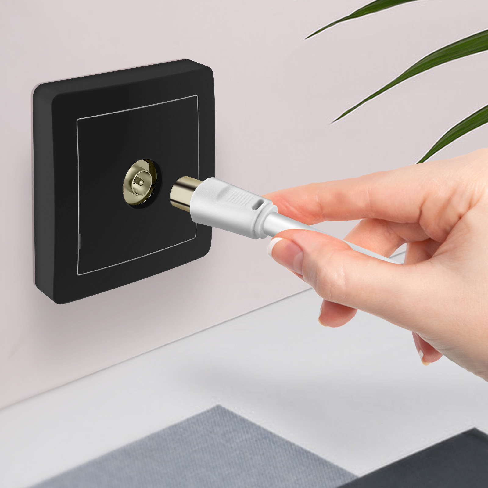 Una mano inserisce un connettore coassiale bianco in una presa a muro nera.