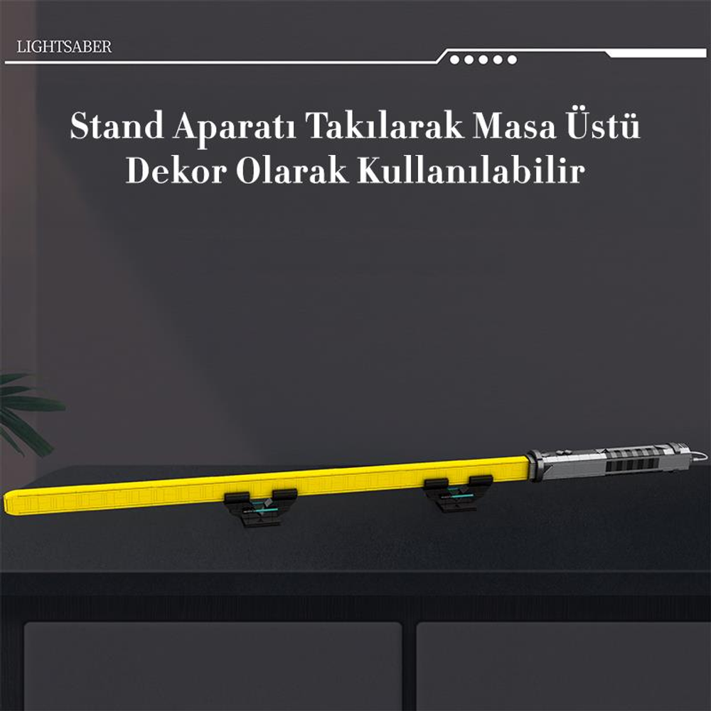 Gümüş detaylı sarı ışın kılıcı kabzası siyah bir masanın üzerinde duruyor.