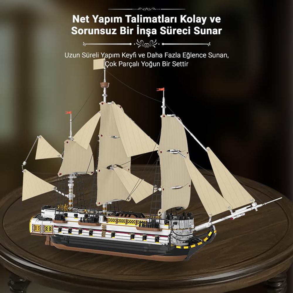 Beyaz yelkenli ve koyu gövdeli detaylı bir model gemi ahşap masada duruyor.