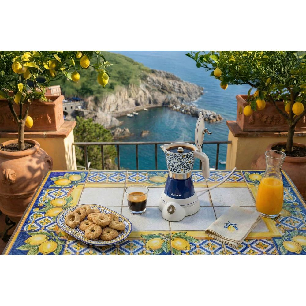 Kaffeemaschine mit Espresso, Keksen und Orangensaft auf einem Tisch mit Meerblick.