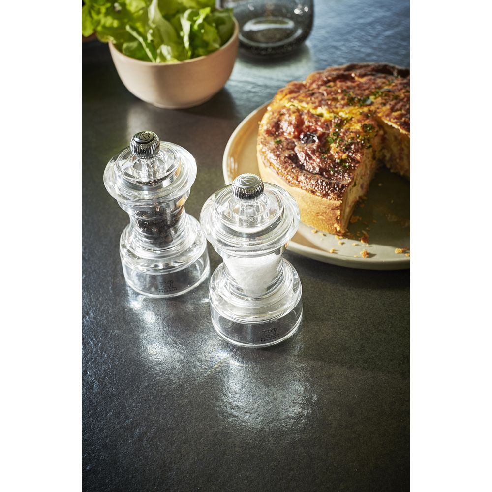 Salz- und Pfeffermühle neben Quiche und Salat.