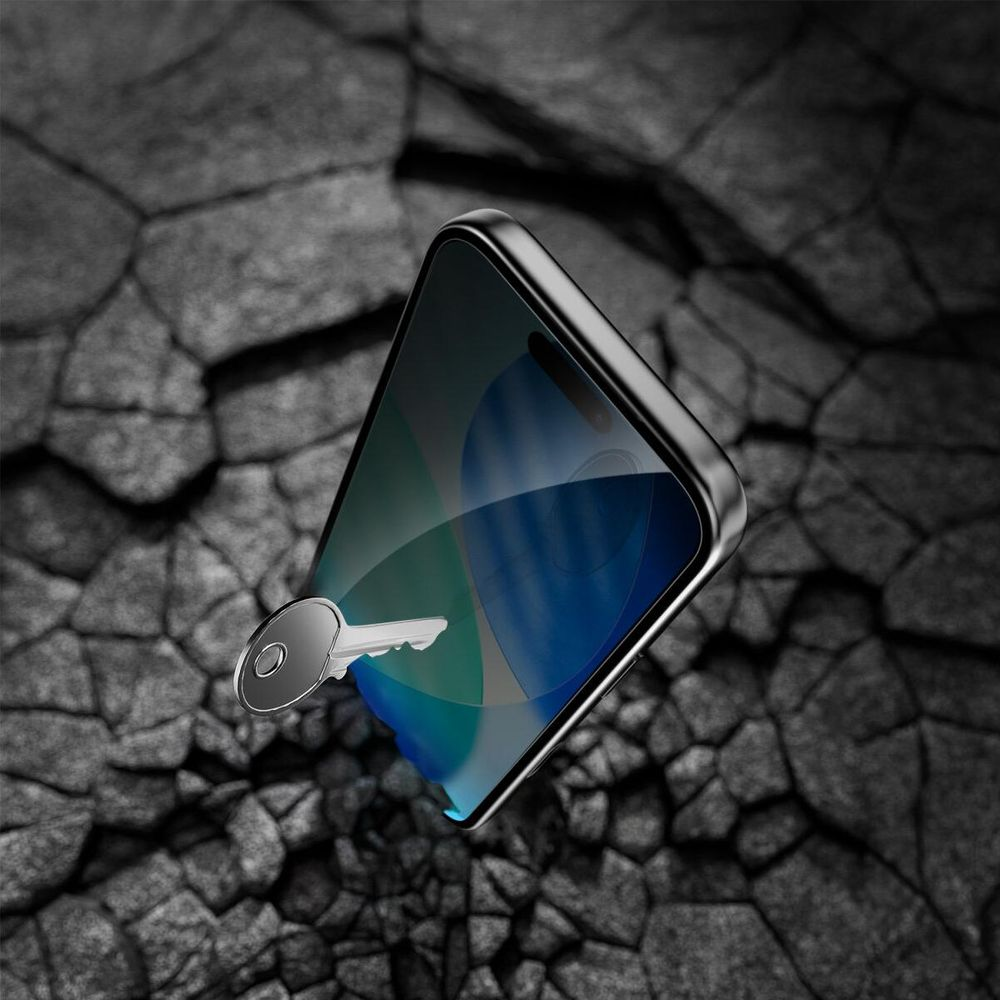 Een zilveren sleutel rust op een donkere, gebarsten achtergrond naast een smartphone.