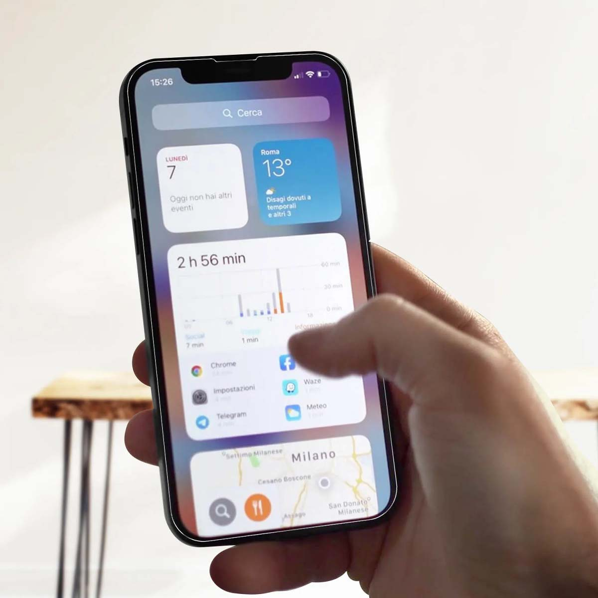 Een hand houdt een smartphone vast met weer- en app-iconen op het scherm.