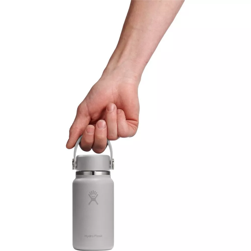 Eine Hand hält eine graue Hydro Flask Wasserflasche an einer Schlaufe.