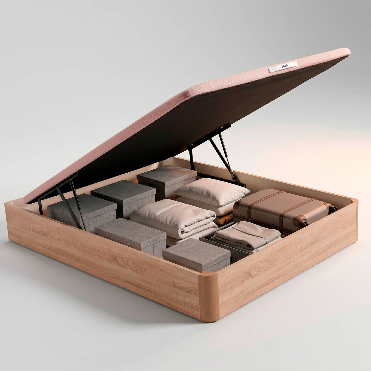 Cama abierta con colchón rosa, ropa de cama plegada, cajas y maleta.
