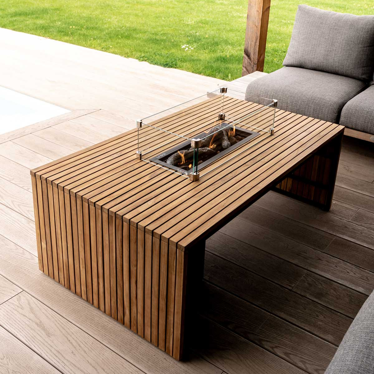Wooden table with integrated gas fire and glass surround on a wooden deck.