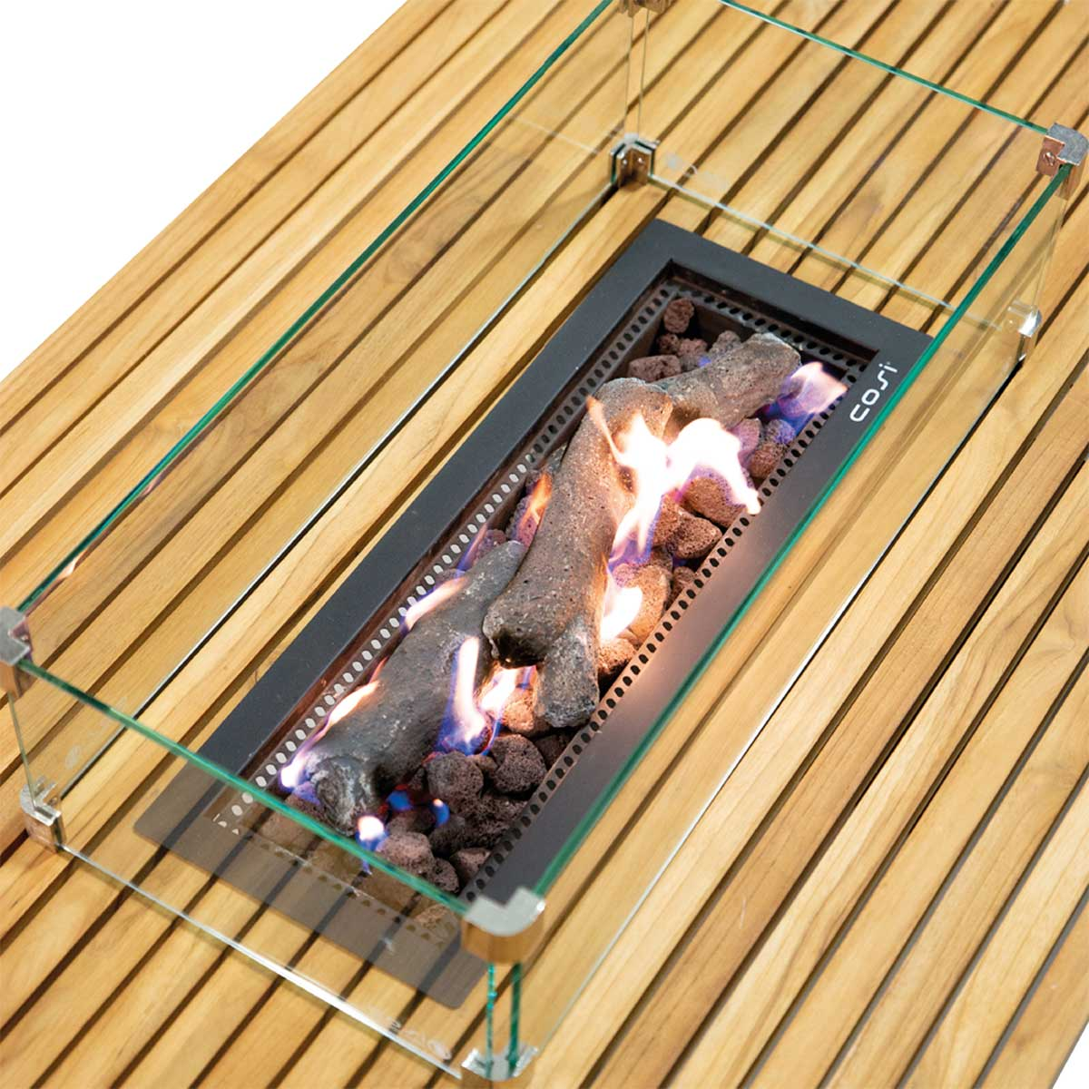 A gas fire pit with glass surround on a wooden table, flames burning.