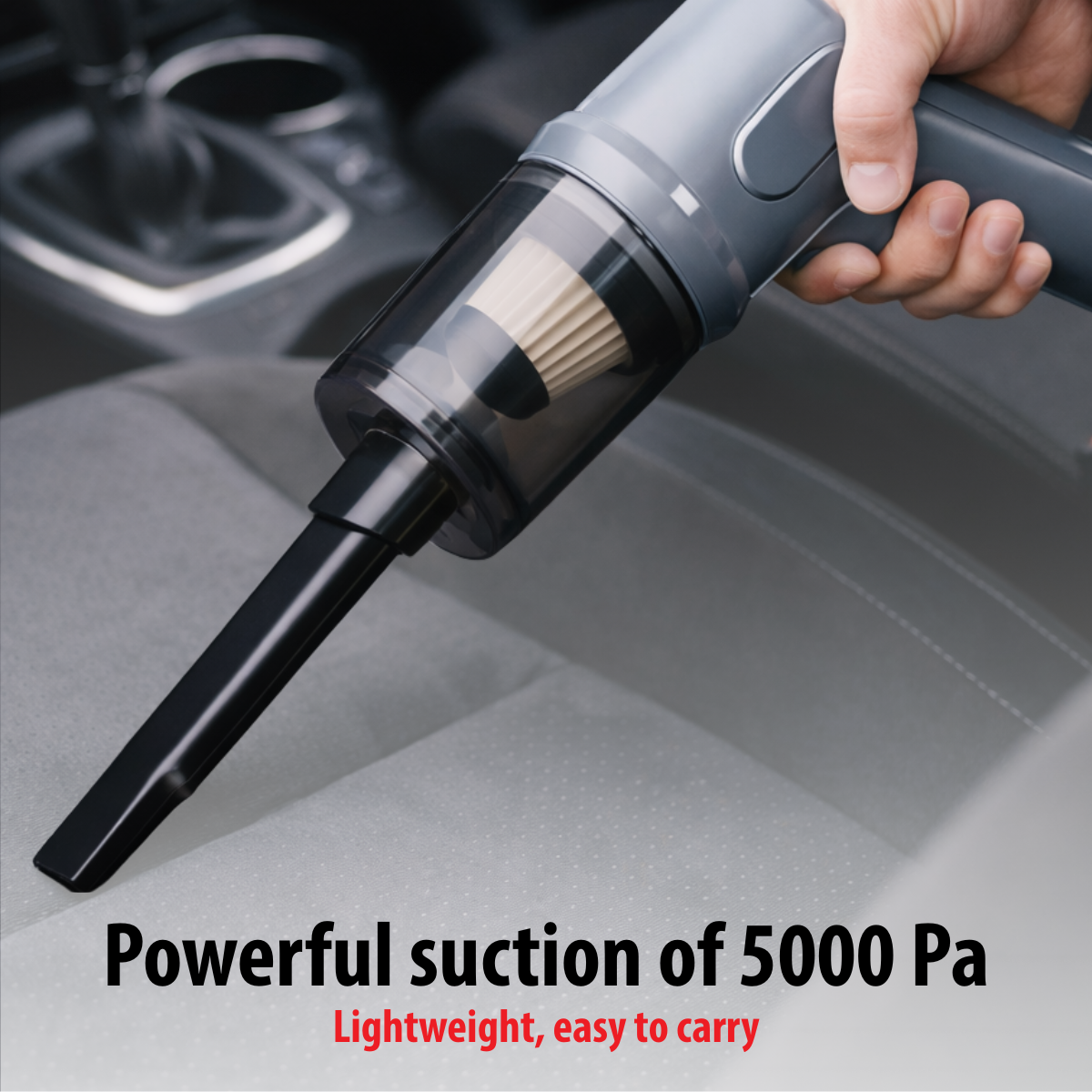 A hand holds a gray portable vacuum cleaner over a car seat.