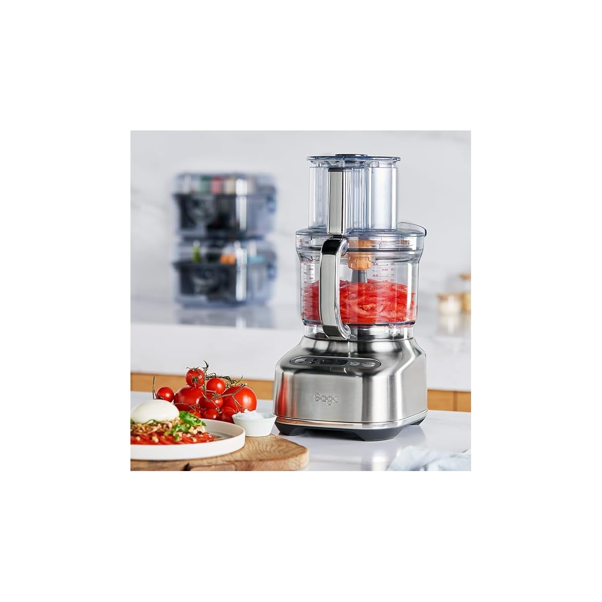 Robot da cucina in acciaio inossidabile con pomodori nella ciotola e su un piatto.