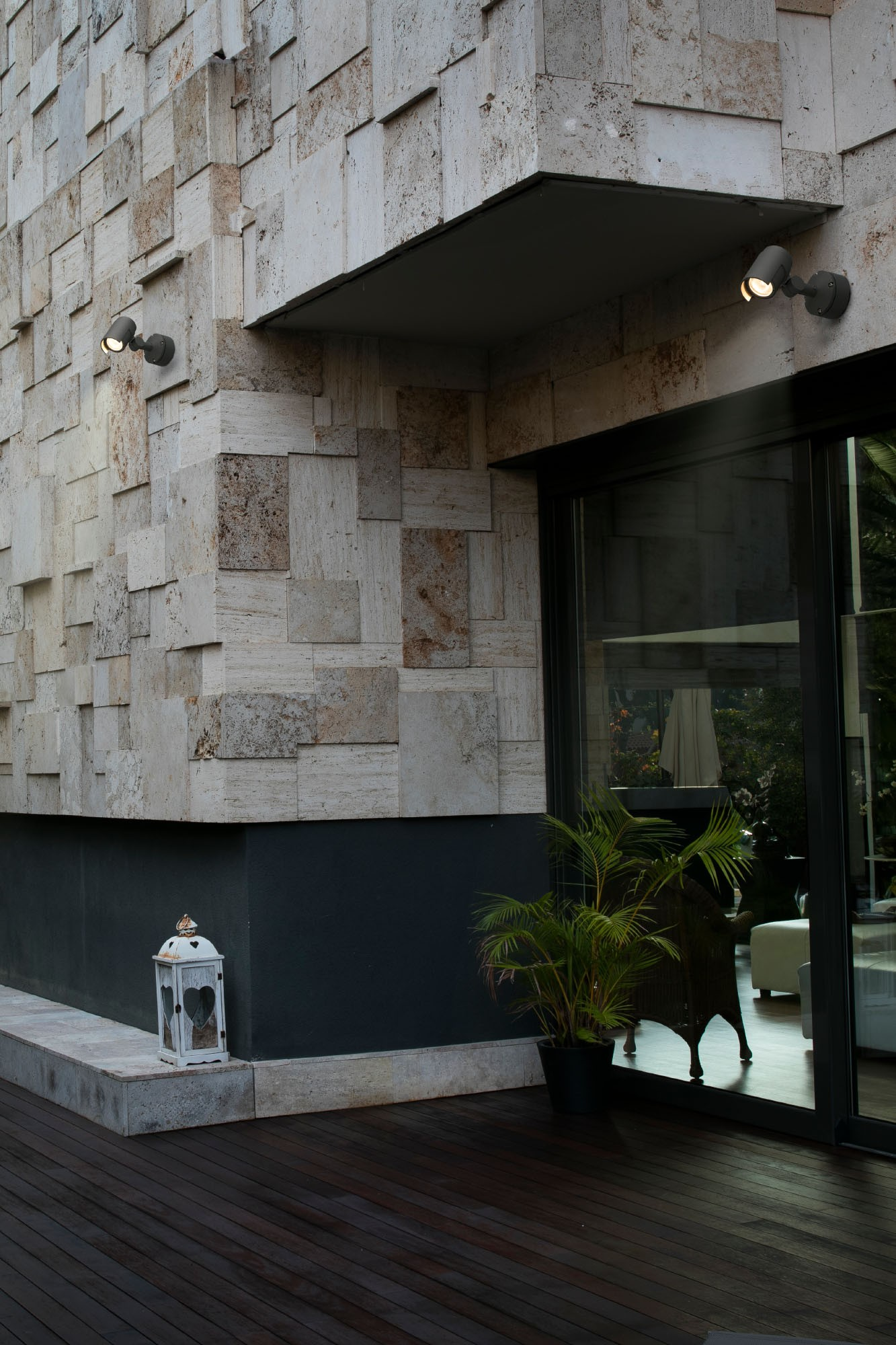 Angolo moderno dell'edificio con facciata in pietra, porta a vetri, lanterna e pianta.