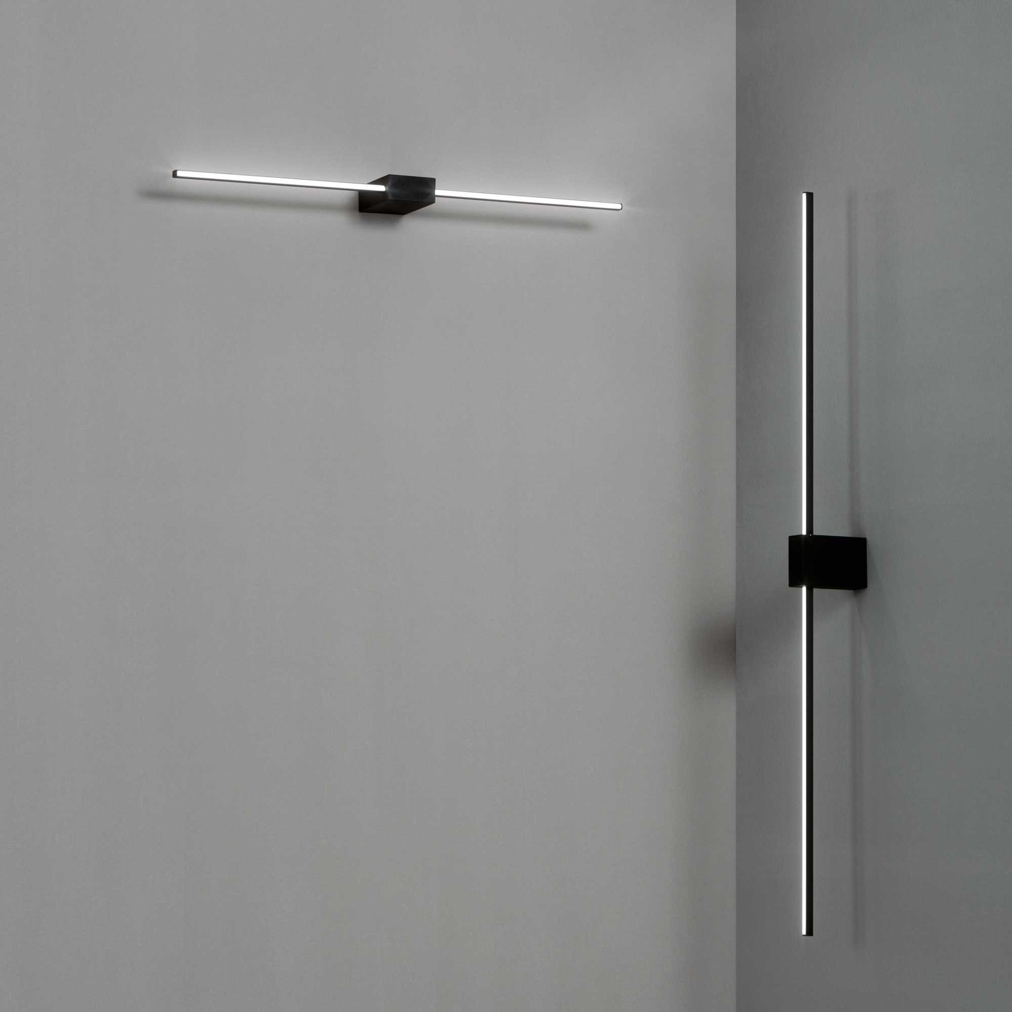 Due applique moderne nere con luce LED lineare su parete grigia.