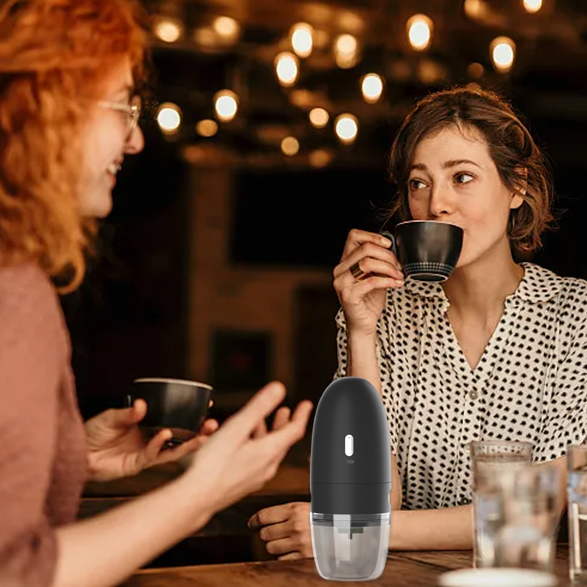 Zwei Frauen trinken Kaffee in einem Café mit Lichterketten im Hintergrund.