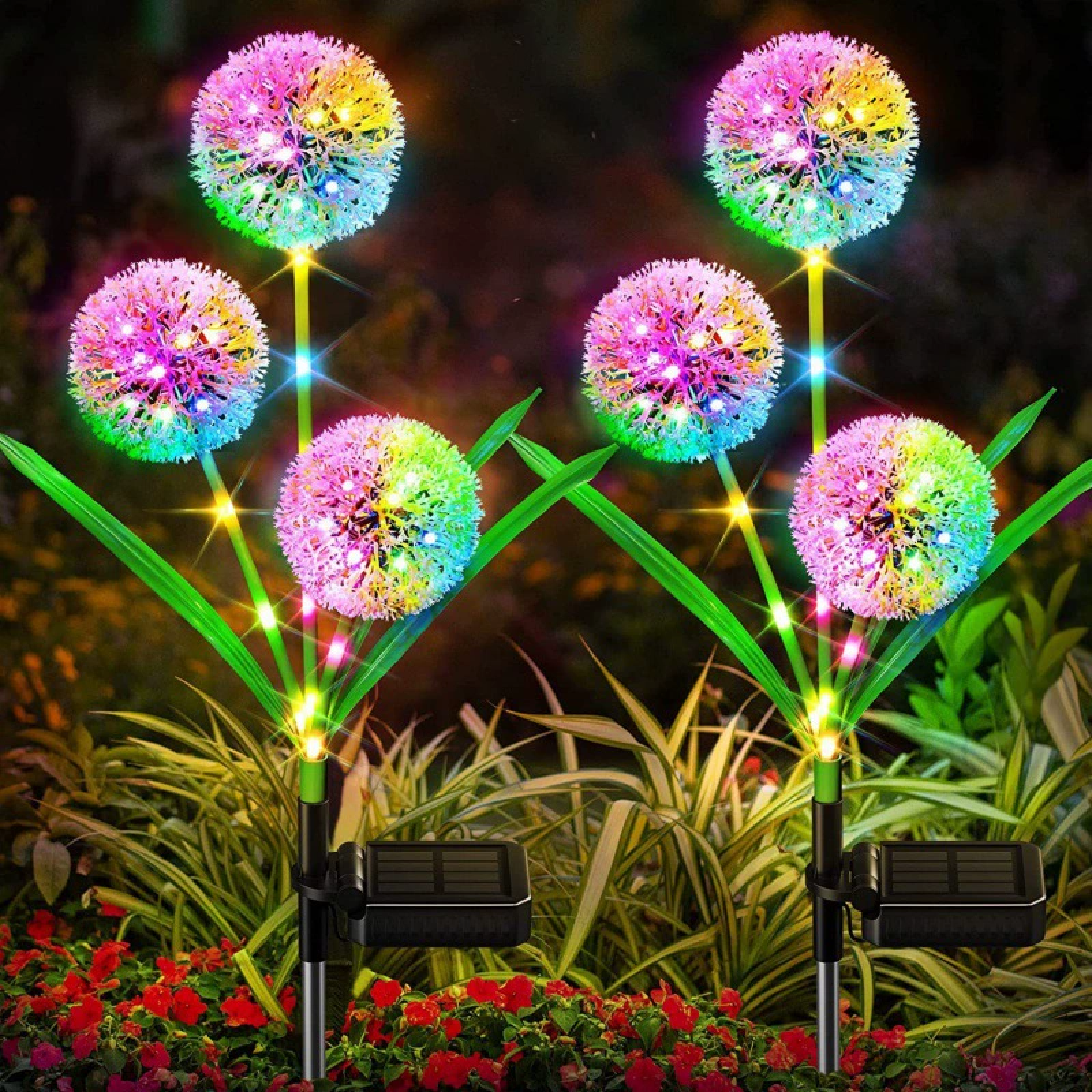 Mehrere bunte Lichterketten in Löwenzahnform leuchten im Garten.