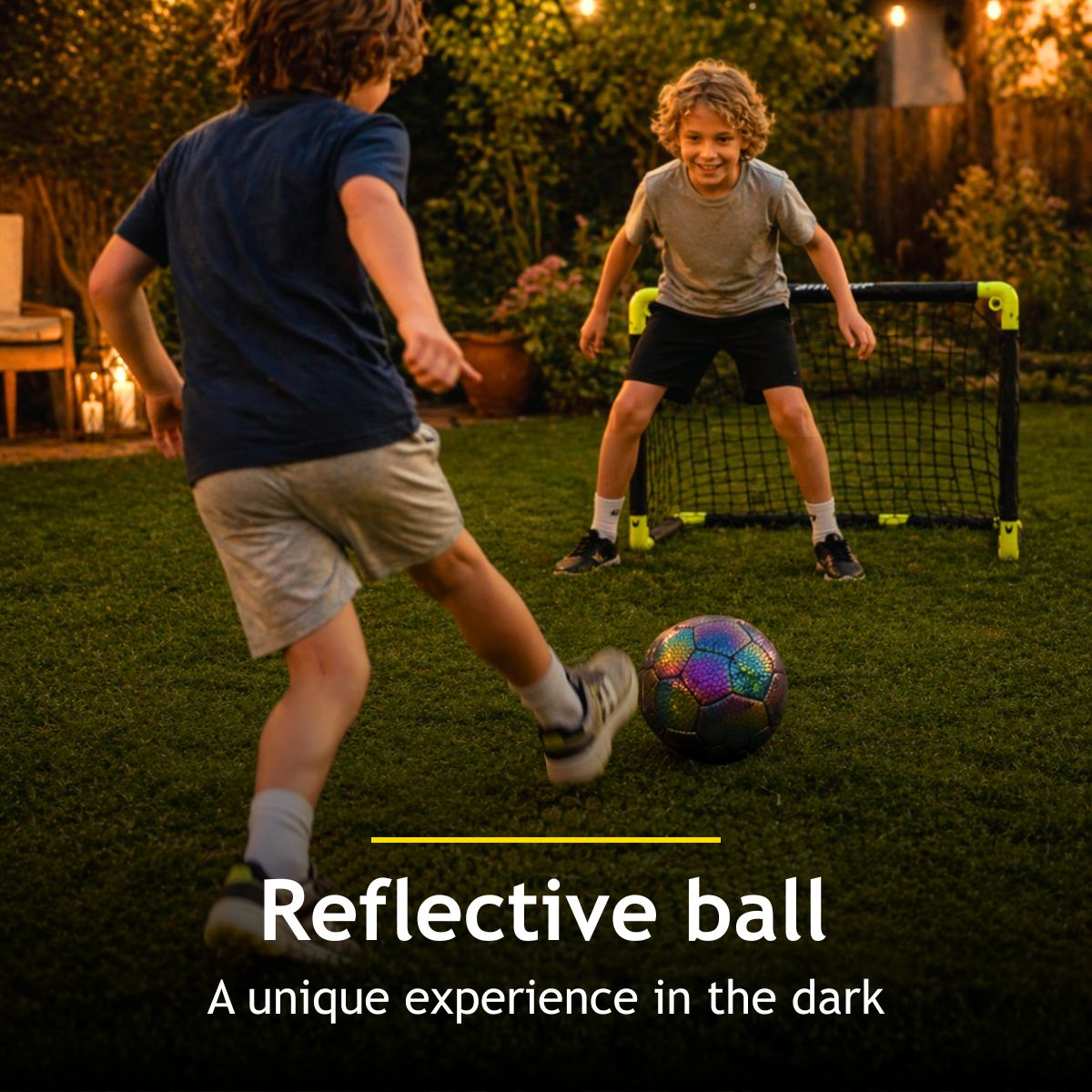 Two boys play soccer at dusk with a reflective ball in a backyard.