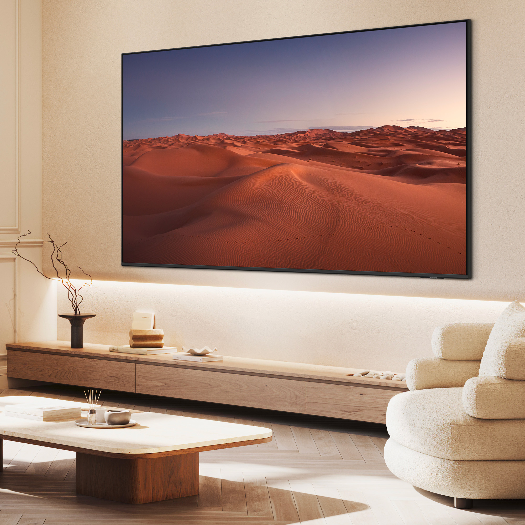 Un grand téléviseur affiche un paysage désertique avec des dunes de sable au coucher du soleil.