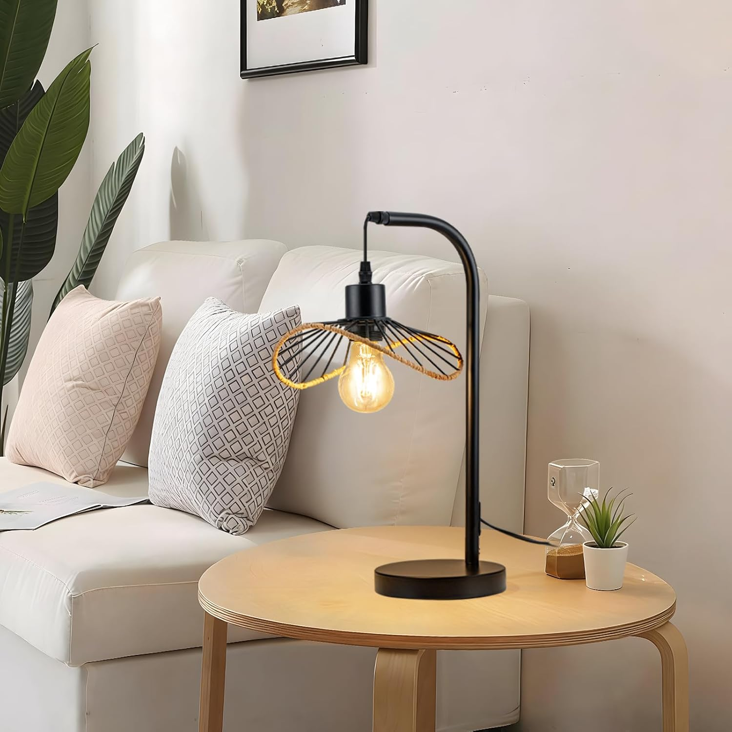 Czarna lampa stołowa z żarówką Edison na okrągłym drewnianym stole.