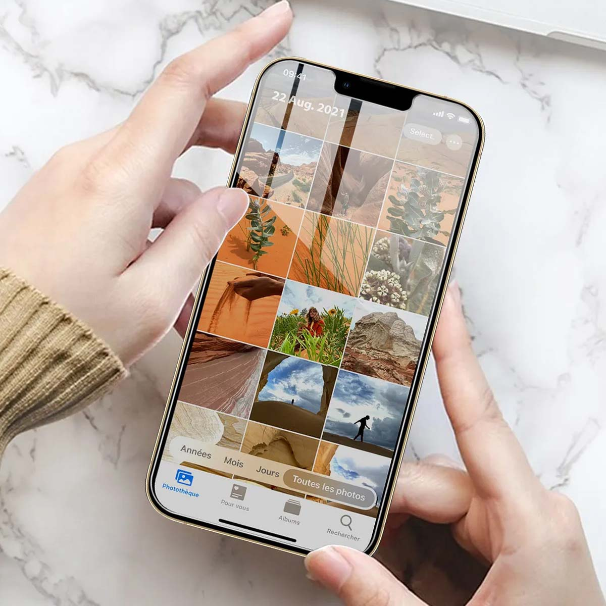 Handen houden een smartphone vast met een fotogalerij van woestijnlandschappen.
